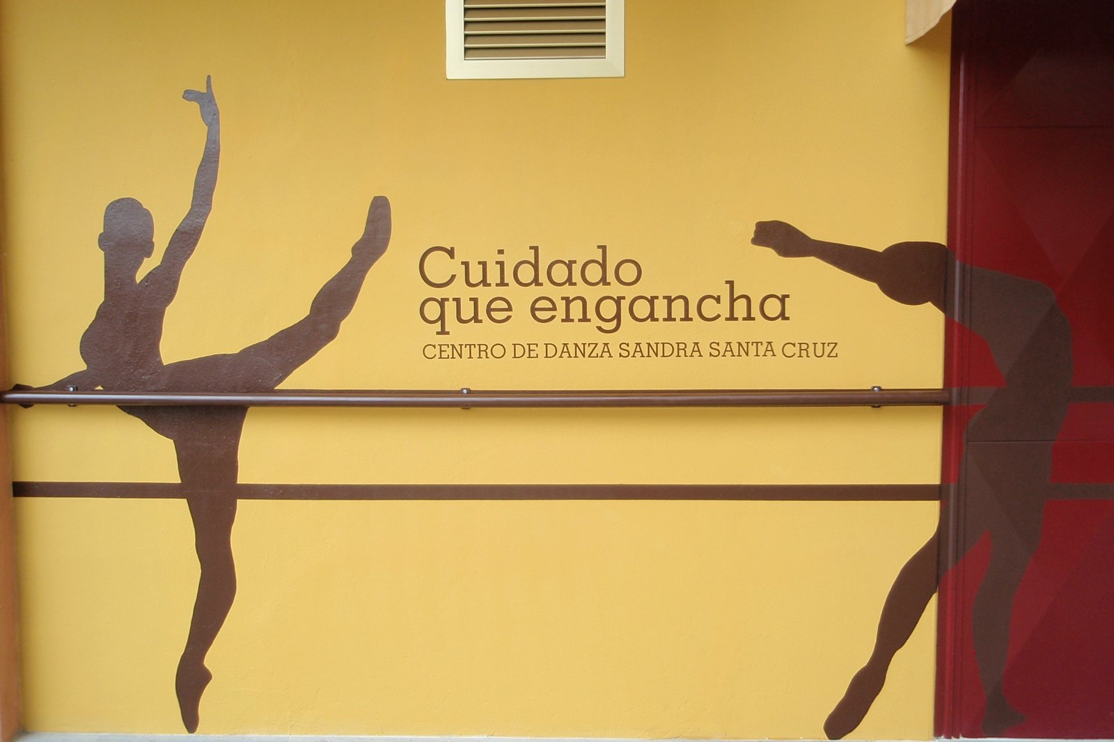 Fachada pintada a tamaño real con la silueta de tres bailarines en diferentes poses y en medio de dos se lee 