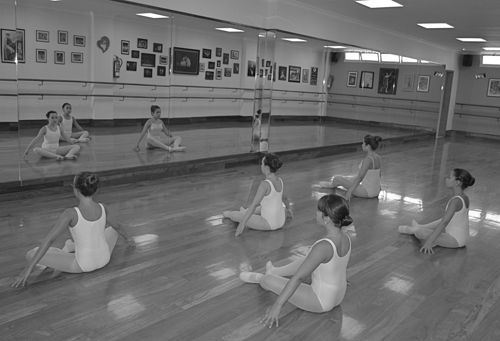 Foto del Centro de Danza Sandra Santa Cruz donde unas alumnas de ballet de nivel Elemental hacen un plié en el suelo en primera posición 