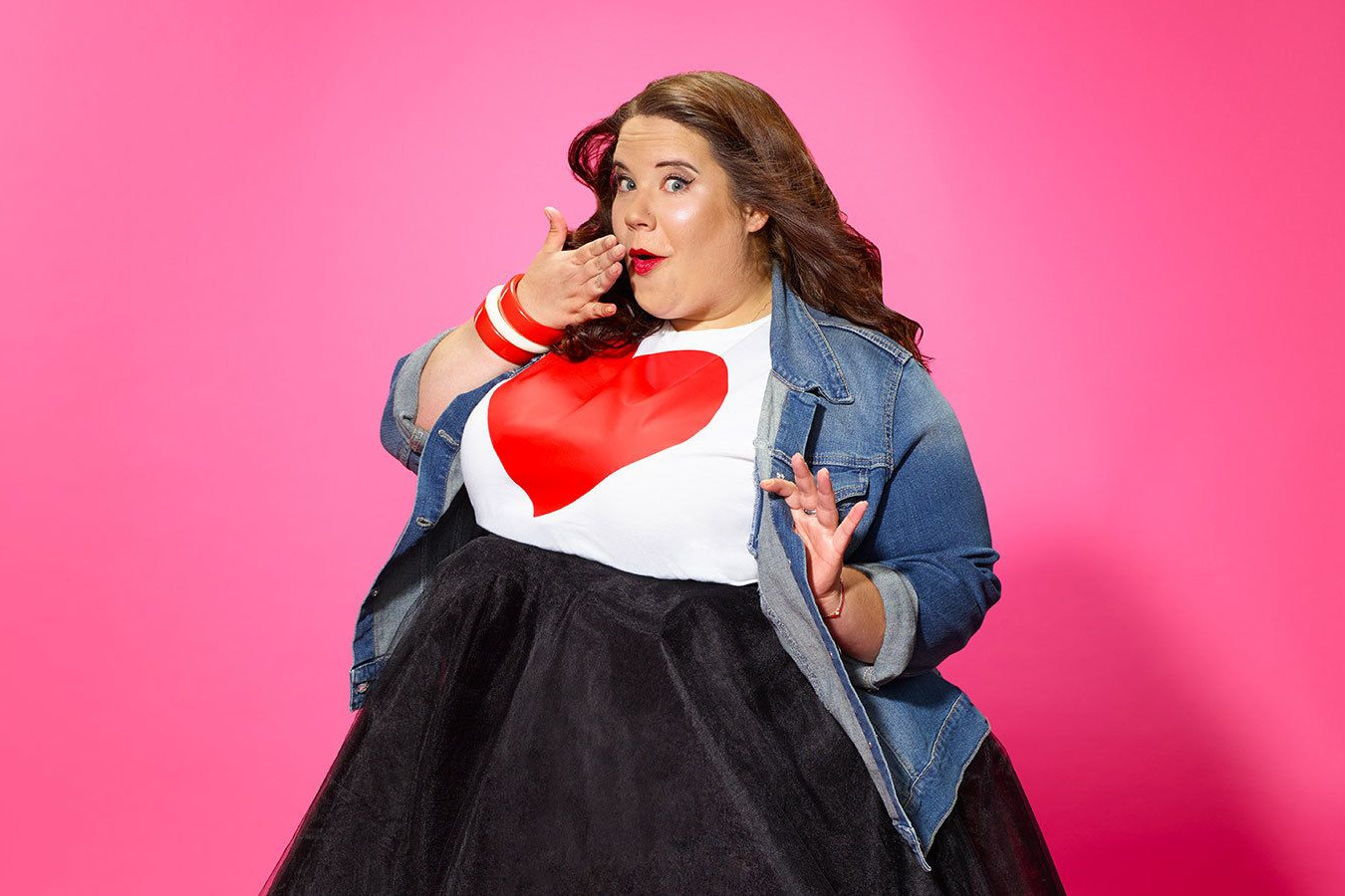 Foto de Whitney Thore con una gran sonrisa y una camisa que tiene un gran corazón