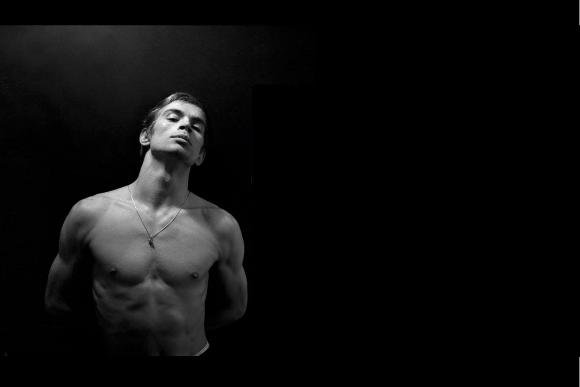 Foto de Rudolf Nureyev_El bailarín a torso descubierto con las manos detrás de la espalda.
