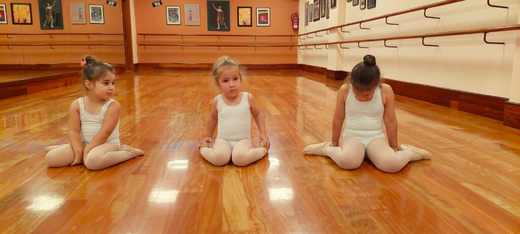 Sentarse en w_Centro de Danza Sandra Santa Cruz Foto de tres alumnas de 3 años sentadas con las rodillas en W en el Centro de Danza Sandra Santa Cruz para explicar el trabajo de anatomía y biomecánica que hace Sandra Santa Cruz en el Centro de Danza.