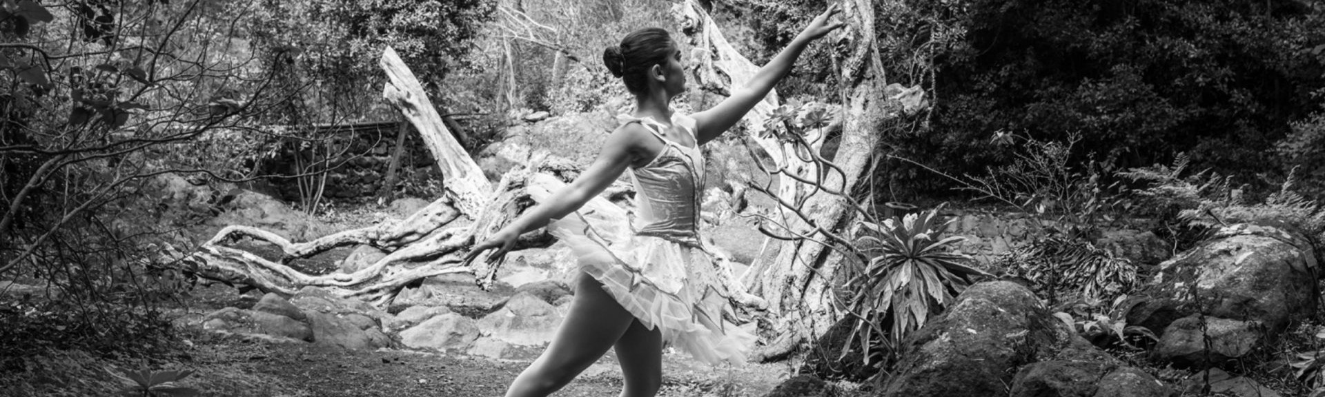 Foto de una bailarina del Centro de Danza Sandra Santa Cruz con un tutú blanco haciendo un arabés en alonyé en el campo.
