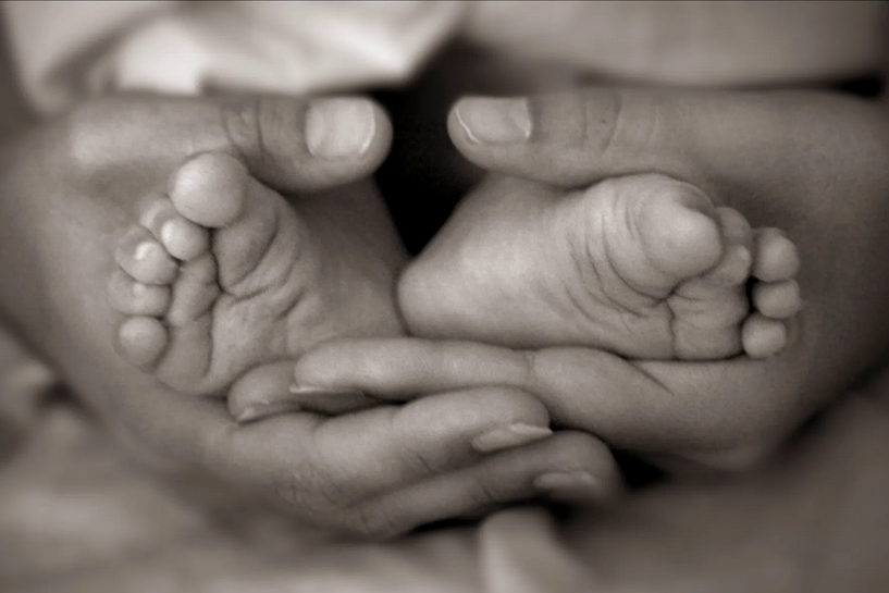 Foto de las manos de una madre abrazando amorosamente los pies de su bebé, con el mismo amor que el Centro de Danza Sandra Santa Cruz vela por al Anatomía de su alumnado.