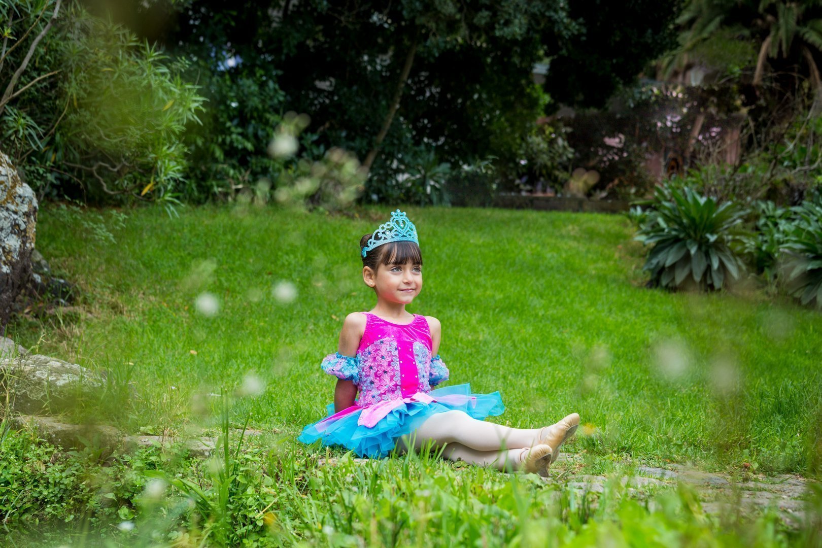 Una niña de 6 años sentada feliz en el Jardín Canario vestida con maravillosos tutú turquesa y fucsia es la foto de bienvenida al curso 20/21 del Centro de Danza Sandra Santa Cruz. Te esperamos para vivir momentos entrañables con nuestro alumnado. Fotografía: Ethel Bartrán.