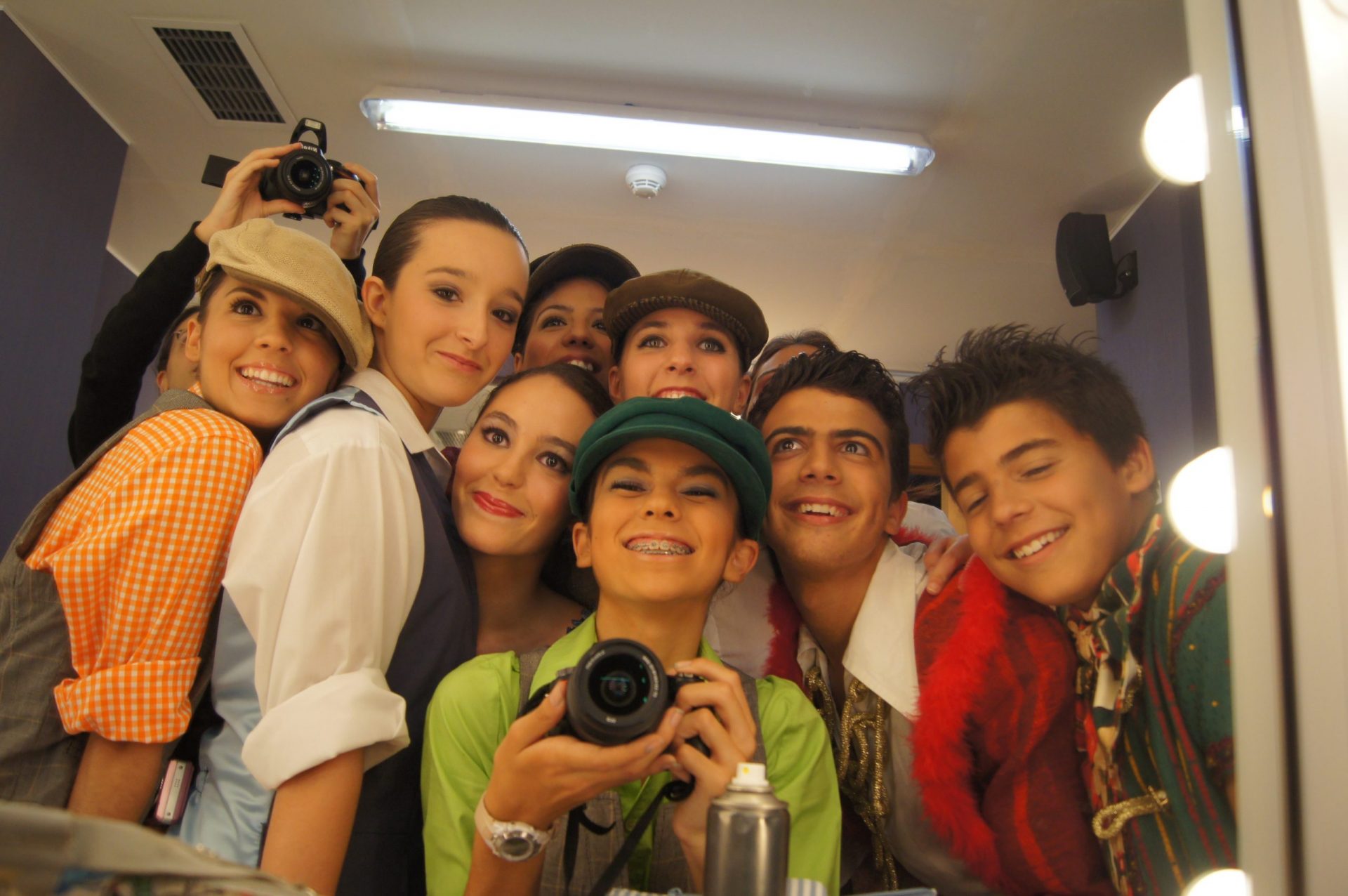 Foto del Centro de Danza Sandra Santa Cruz donde un grupo de alumno posa mirándose al espejocon una amplia sonrisa y la bailarina del centro lleva una cámara de fotos.