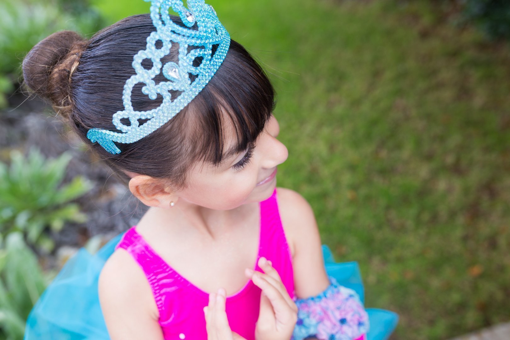 Foto en el campo de una alumna de 6 años Centro de Danza Sandra Santa Cruz vestida con tutú fucsia y malva y una diadema de princesa con las manos haciendo 