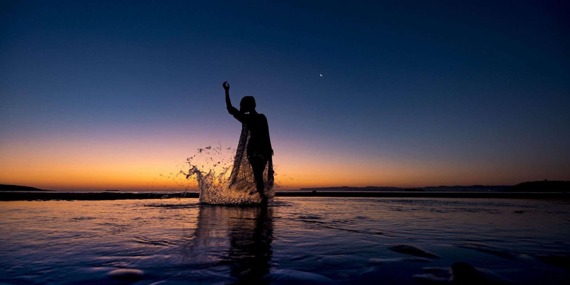 Foto de un precioso atardecer con una chica a contraluz salpicando agua en el mar. Dance Together_Centro de Danza Sandra Santa Cruz_Ethel Bartrán_DSC6079