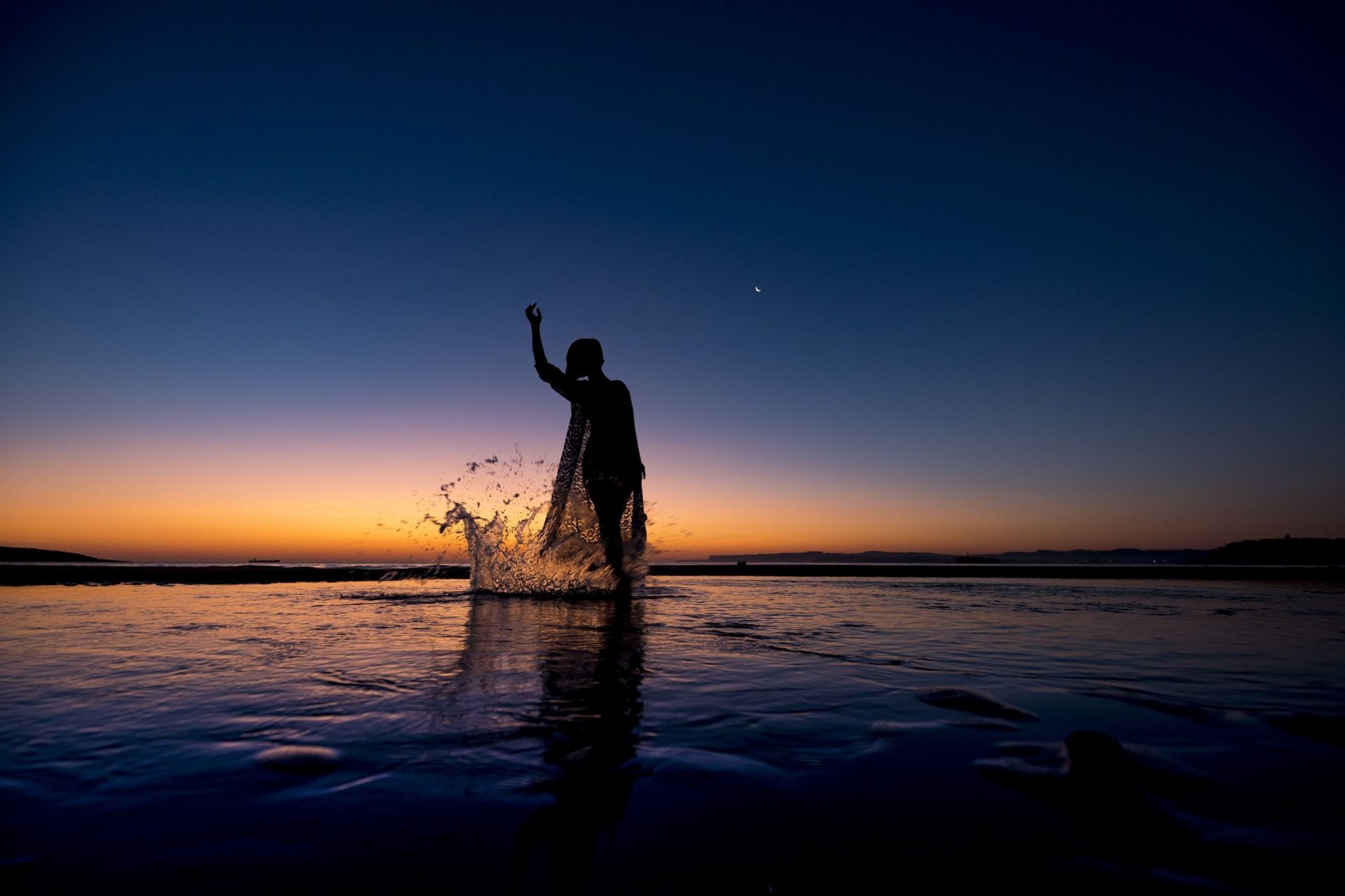 Foto de un precioso atardecer con una chica a contraluz salpicando agua en el mar. Dance Together_Centro de Danza Sandra Santa Cruz_Ethel Bartrán_DSC6079