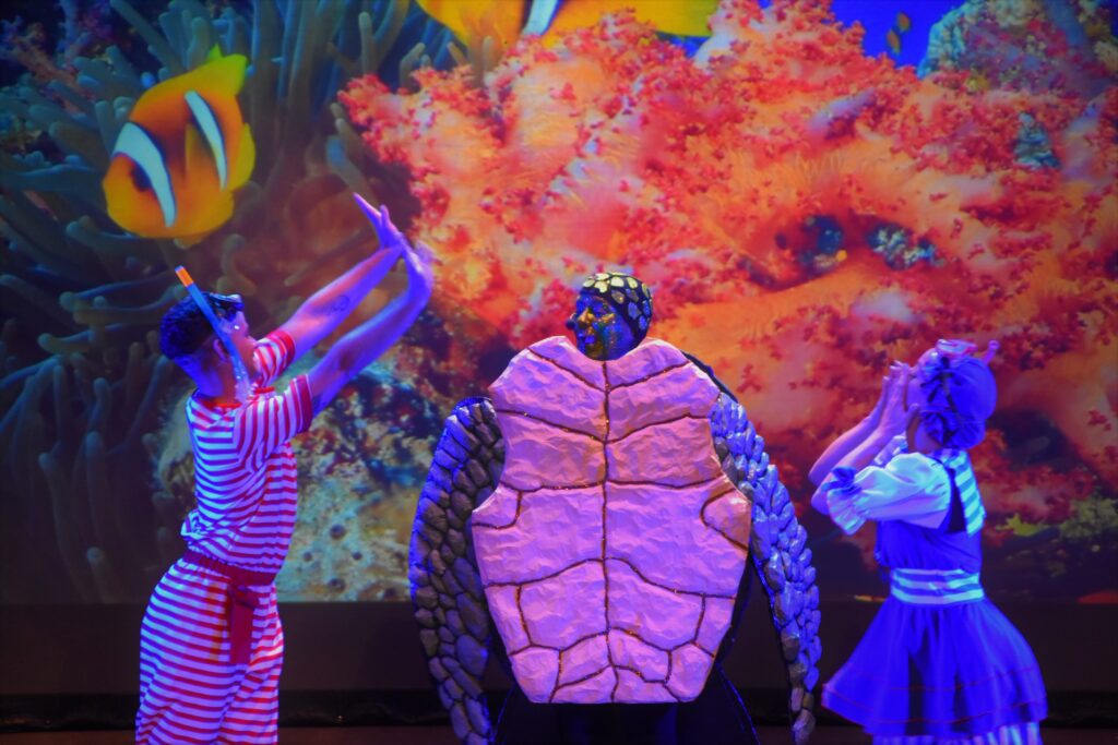 Doña Paciencia, la tortuga más sabia de "Si los peces hablaran..." es liberada del plástico por dos humanos. Nos encantaría dar a conocer la relevancia de esta obra en Disneyland París.